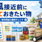 台風接近前に確認したい防災用品をまとめたアイキャッチ画像。 飲料水、缶詰、アルファ米、カップ麺、乾電池、懐中電灯、LEDランタン、保冷剤、保冷バッグなどを並べ、水・食料・電池・保冷用品の最終チェックを表している。 背景には雨雲と強風が近づく住宅が描かれ、台風前に自宅の在庫を確認し、不足分だけを無理なく補充する大切さを伝えている。